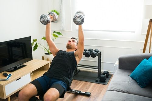 אדם מבצע אימון משקולות בסלון ביתו
